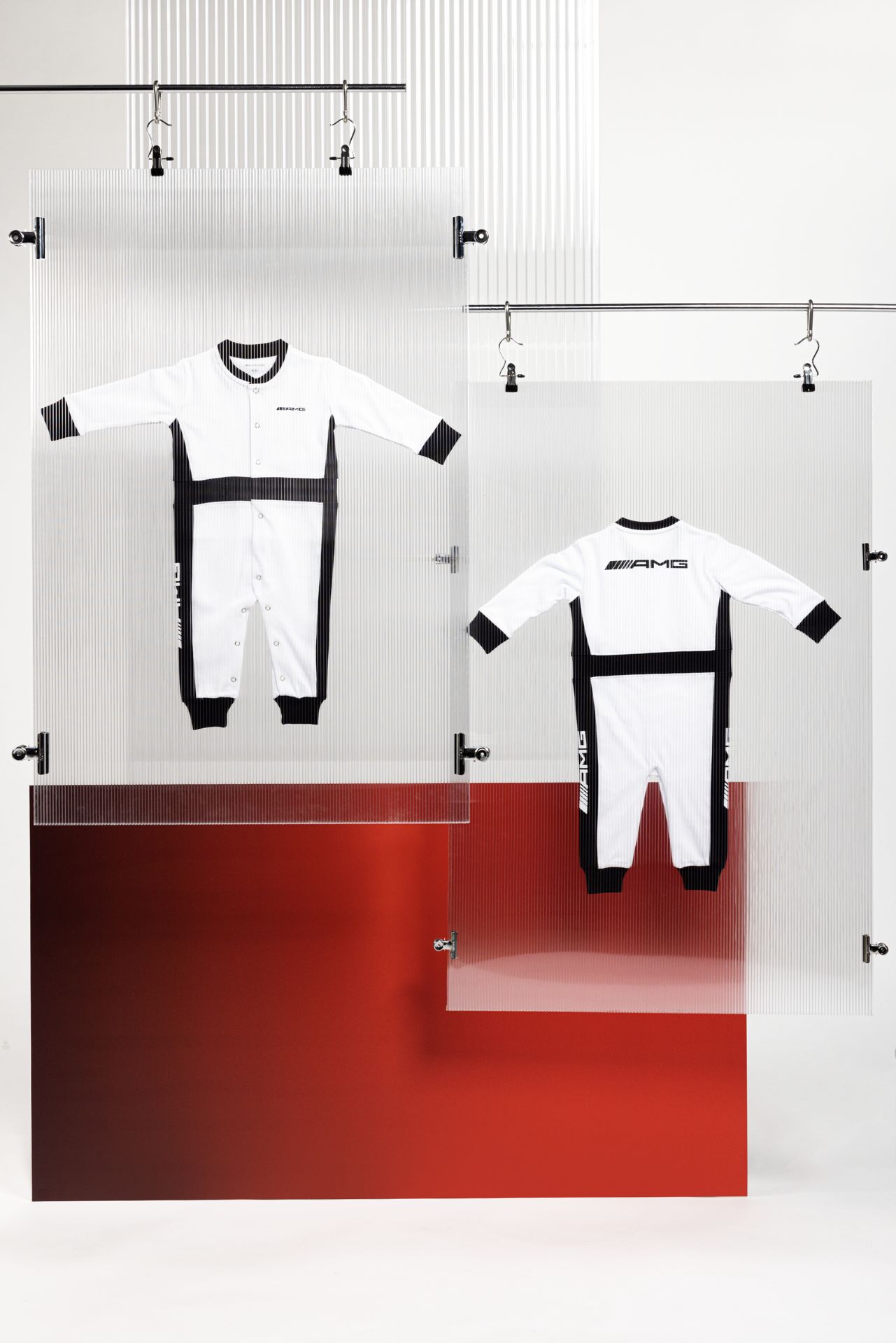 Zwei Babystrampler B66959635 von AMG, schwarz-weiß, aufgehängt an einer Kleinerstange. Zwei Babystrampler B66959635 von AMG, schwarz-weiß, aufgehängt an einer Kleinerstange. Verlinkt auf die Kategorie: Mode_Kids